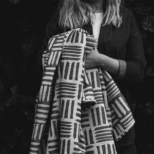 British textile designer Beatrice Larkin holding one of her monochrome merino wool throws