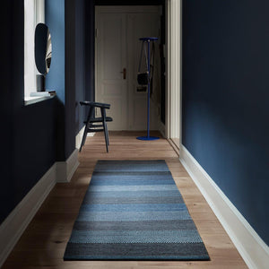 Fabula Living’s Blue Veronica Rug in a dark blue hallway on a light wooden floor.  - designed by Lisbet Friis.
