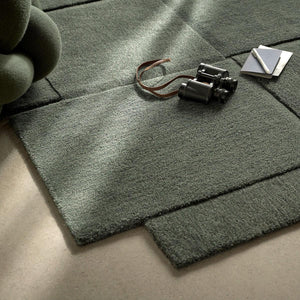 Corner of Design House Stockholm wool green Basket rug with binoculars and notebook