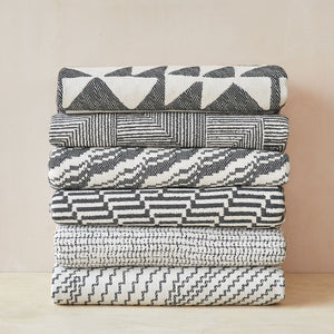 Beatrice Larkin woven merino wool blankets folded and stacked, showing geometric patterns 