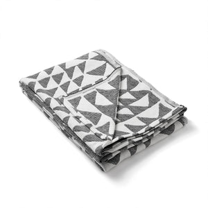 Beatrice Larkin Flint Throw in Merino wool with gentle triangle geometric pattern. Throw folded. 
