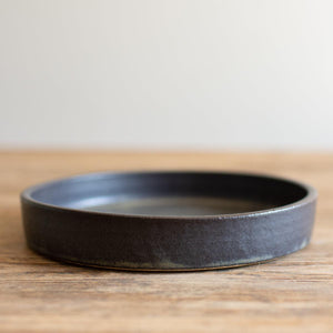 Hand-thrown artisan tapas dish. Ceramic tableware handmade by Carla Murdoch in the UK. The tapas dish has a dramatic black glaze with golden and khaki tones.