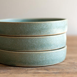 Stack of three hand-thrown artisan tapas dishes. Ceramic tableware handmade by Carla Murdoch in the UK. The tapas dishes have an earthy green lichen colour glaze.
