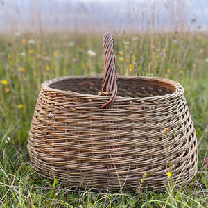 Woven willow basket with handle, handmade by basket maker Catherine Beaumont, using English grown natural willow.  In an English meadow.