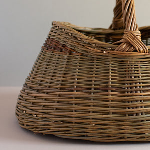 Woven willow basket with handle, handmade using various natural willow varieties to create coloured details. Looking at the weave close up. 