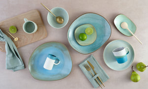 Eye-catching aqua blue glazed ceramic tableware displayed on a table with fruit garnishes and cutlery