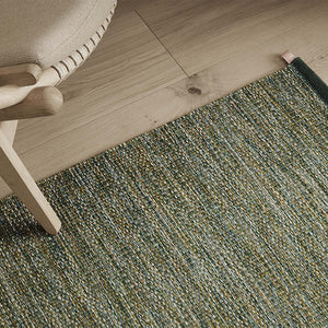 Kasthall summer breeze greta flatweave rug in green tones, on wooden flooring with chair