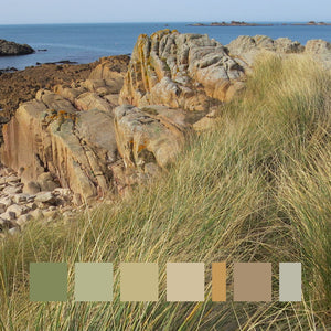 Rocky coastal landscape with granite reef next to gold and green grasses, blue ocean and sky. The granite reef colours range from pale pinks to rich browns.