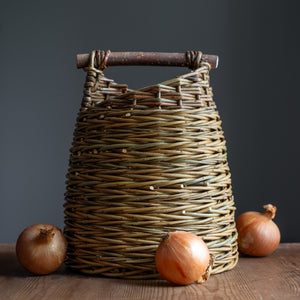 Willow asymmetric basket with willow handle pictured with onions. Basket handmade by Rachel Bower, photo by Manna Reid.