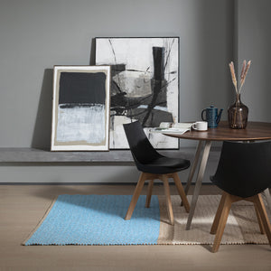Recork Sugo Rug made from sustainable cork and linen pictured in contemporary dining room set. Rug is blue, beige and cream.
