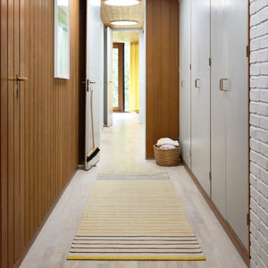 Fabula Living’s Poppy Rug is designed by Lisbet Friis.  A refreshing yellow and beige striped design handwoven in wool and linen. The rug has a fine, tightly woven texture and is also reversible. Rug shown in wooden clad hallway