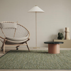 Kasthall's Summer Breeze Greta rug with contemporary wood framed armchair, earthy coloured side table and wooden decorative objects on shelf in background.