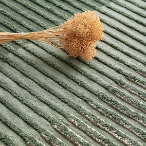 Tacto's Campos Green Rug, close up with dried flowers - designed by Aranda Aloy Enblanc.