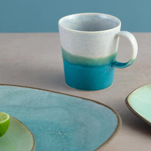 Aqua Blue Glazed Porcelain Mug by SGW Lab in grey, aqua and turquoise. Mug on table with blue ceramic plates.