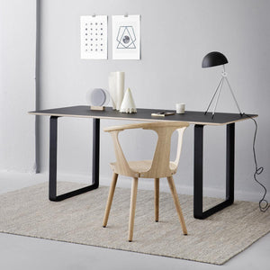 Fabula Living’s Beige/Grey Gimle Rug, placed in a light coloured room with a dark desk and wooden chair on top - designed by Jens Landberg Schrøder