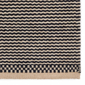 A close up image of the Fabula Living’s Black/Beige Daisy Rug which is designed by Lisbet Friis.  Through the harmonious pairing of woven pattern and warm black/beige colours, the gentle two-tone stripe brings an extra dimension to this flat weave rug. Finished with a chequered pattern at each end to frame the design.