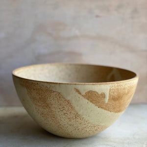 The Brown Oda Salad Bowl is a large size bowl with a minimalist form and distinctive use of colours and glazes, here sat on a workbench - by Julie Damhus.