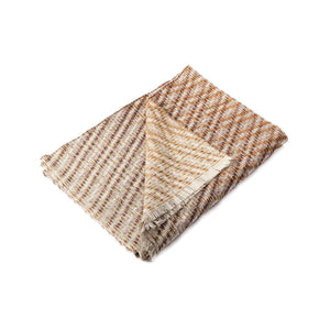 The Bristol Weaving Mill Wool and Linen Blanket in earthy brown tones is folded with the corner turned back to show the complex diagonal, criss-cross, weave pattern. 
