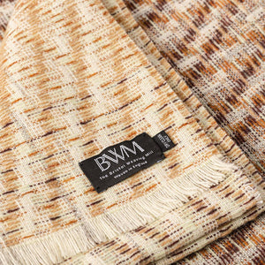 The Bristol Weaving Mill Wool and Linen Blanket in earthy brown tones is folded with the corner turned back to show the brand and care label. 