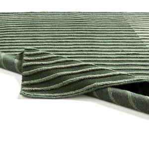 Tacto's Campos Green Rug, ruffled on the floor showing both the top and underneith of the rug - designed by Aranda Aloy Enblanc.