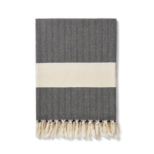 charcoal herringbone pattern blanket with contrasting cream band finished with a cream knotted fringe at each end. Ferah organic cotton blanket by Lüks. 
