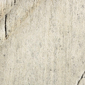 A closer look ate the texture of the Fields Natural Landscape Rug with a deep charcoal abstract pattern appearing etched into the soft beige wool pile in this wonderfully textured rug - by Rezas