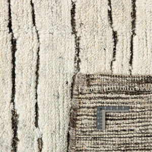A closer look ate the texture of the Fields Natural Landscape Rug with a deep charcoal abstract pattern appearing etched into the soft beige wool pile in this wonderfully textured rug - by Rezas