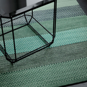 Fabula Living’s Green Veronica Rug sat on a dark wood floor with a side table sat on the rug - by Lisbet Friis.