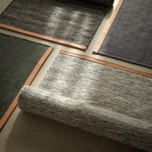 Four Design House Stockholm Bjork Rugs with leather edges, partially unrolled on the floor.