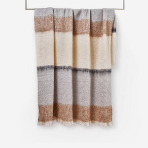 Owl Silare mohair throw blanket by Cushendale, features block stripes of chestnut, warm grey and cream. Shown handing on a rail. 