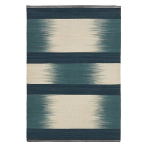Hand dyed and flatwoven blue rug featuring bold stripes and Ptolemy Mann's signature ikat design. Blue block stripes with ikat stripes.