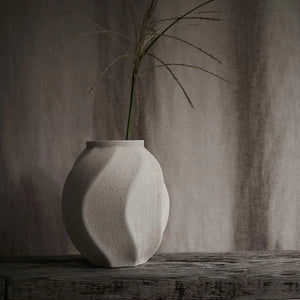 Lindform’s Soft Wave sand light Ceramic Vase, This sculptural ceramic vase has a natural, sandy beige coloured matt finish on the outside and is glazed on the inside. with one flower, placed on wooden bench
